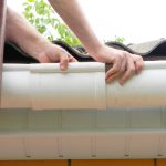 Contractor installing plastic roof gutter pipeline