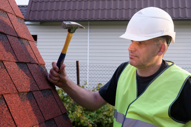 Roof repair worker with a hammer