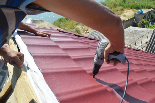 Roofing contractors installing metal roof tile for roof repair